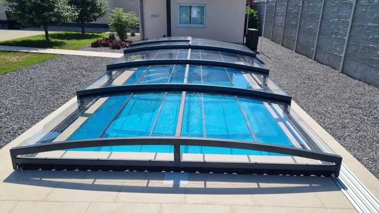 Une abri de piscine moderne et bas, doté d'un revêtement transparent, dans le jardin