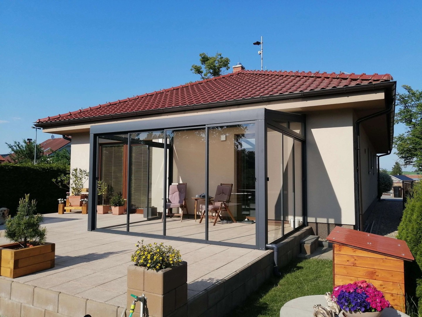 Une véranda moderne vitrée, avec une structure anthracite, sur la terrasse d'une maison individuelle