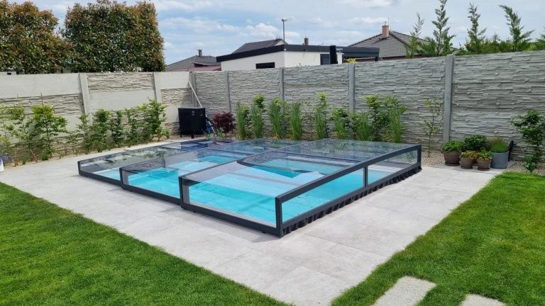 Une couverture de piscine moderne et basse, dotée d'un revêtement transparent, dans le jardin