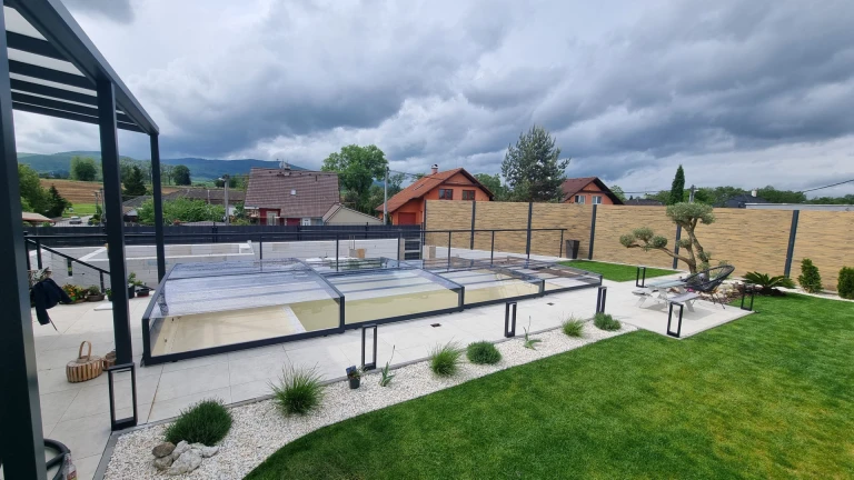 Une couverture de piscine moderne et basse dans le jardin d'une maison individuelle avec vue sur les collines.