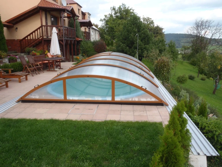 Une verrière arquée fermée au-dessus de la piscine, sur la terrasse d'une maison individuelle.