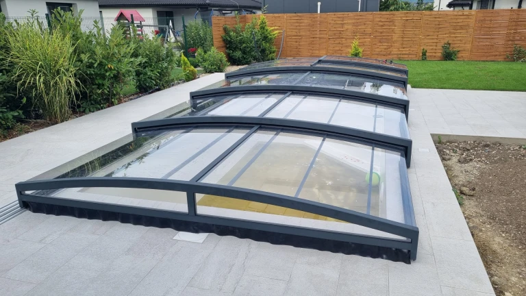 Une couverture de piscine moderne et basse, de couleur anthracite, sur la terrasse d'une maison individuelle