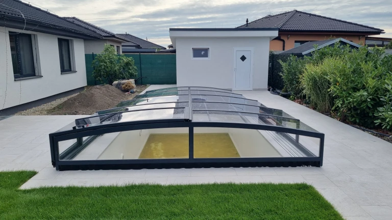 Une petite verrière anthracite sur la piscine, située sur la terrasse moderne d'une maison individuelle