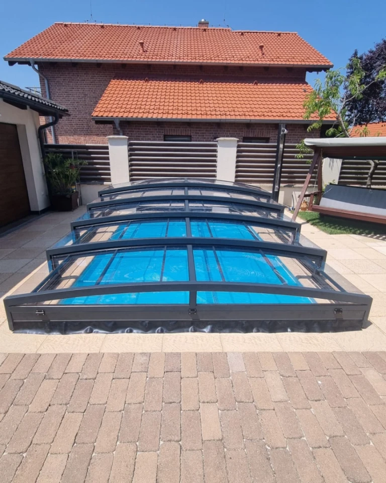 Une couverture de piscine moderne et basse, de couleur anthracite, dans la cour d'une maison individuelle