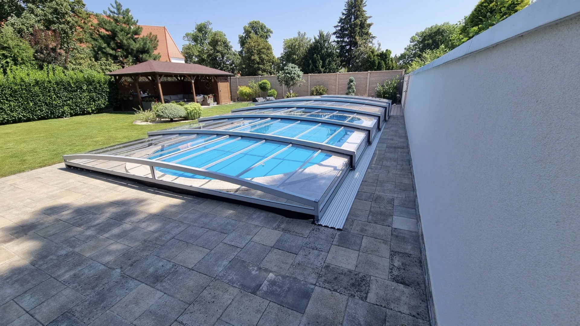 Une couverture de piscine moderne et basse PREMIER, dotée d'un revêtement transparent, dans un jardin à Modra