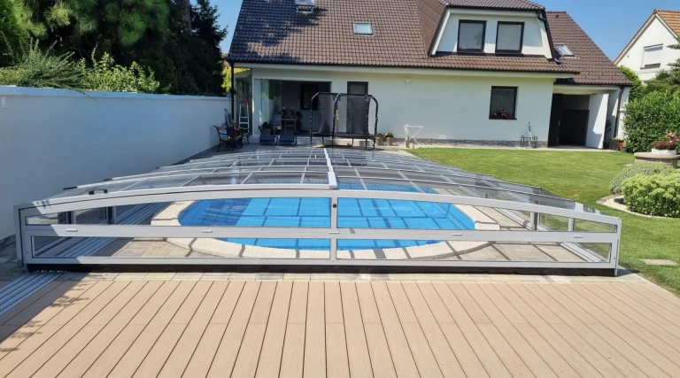 Une couverture de piscine moderne et basse, dotée de panneaux translucides, dans le jardin d'une maison individuelle
