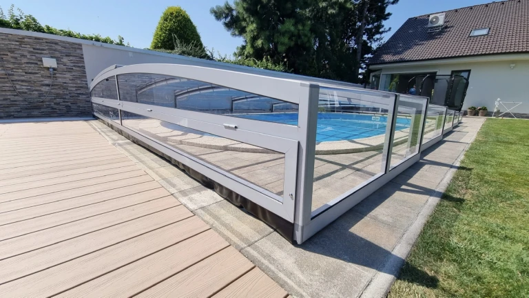 Une couverture de piscine moderne et basse, dotée d'un revêtement transparent, dans le jardin d'une maison individuelle.