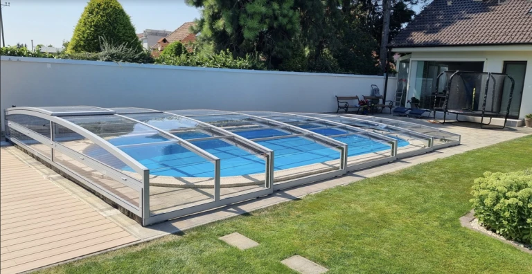 Une couverture de piscine moderne et basse, dotée d'un revêtement transparent, dans le jardin d'une maison individuelle