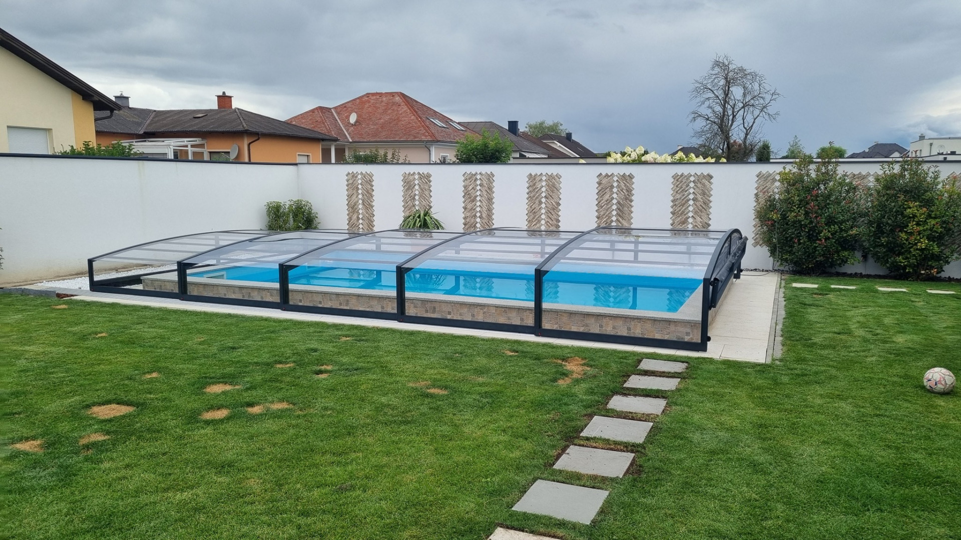 Une couverture de piscine moderne et basse, de couleur anthracite, dans un jardin avec une pelouse