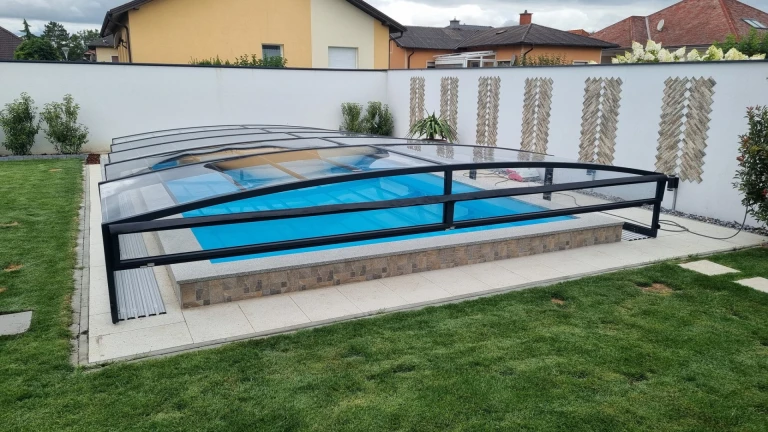 Une couverture de piscine moderne et basse, dotée d'une structure noire, au-dessus d'une piscine de jardin