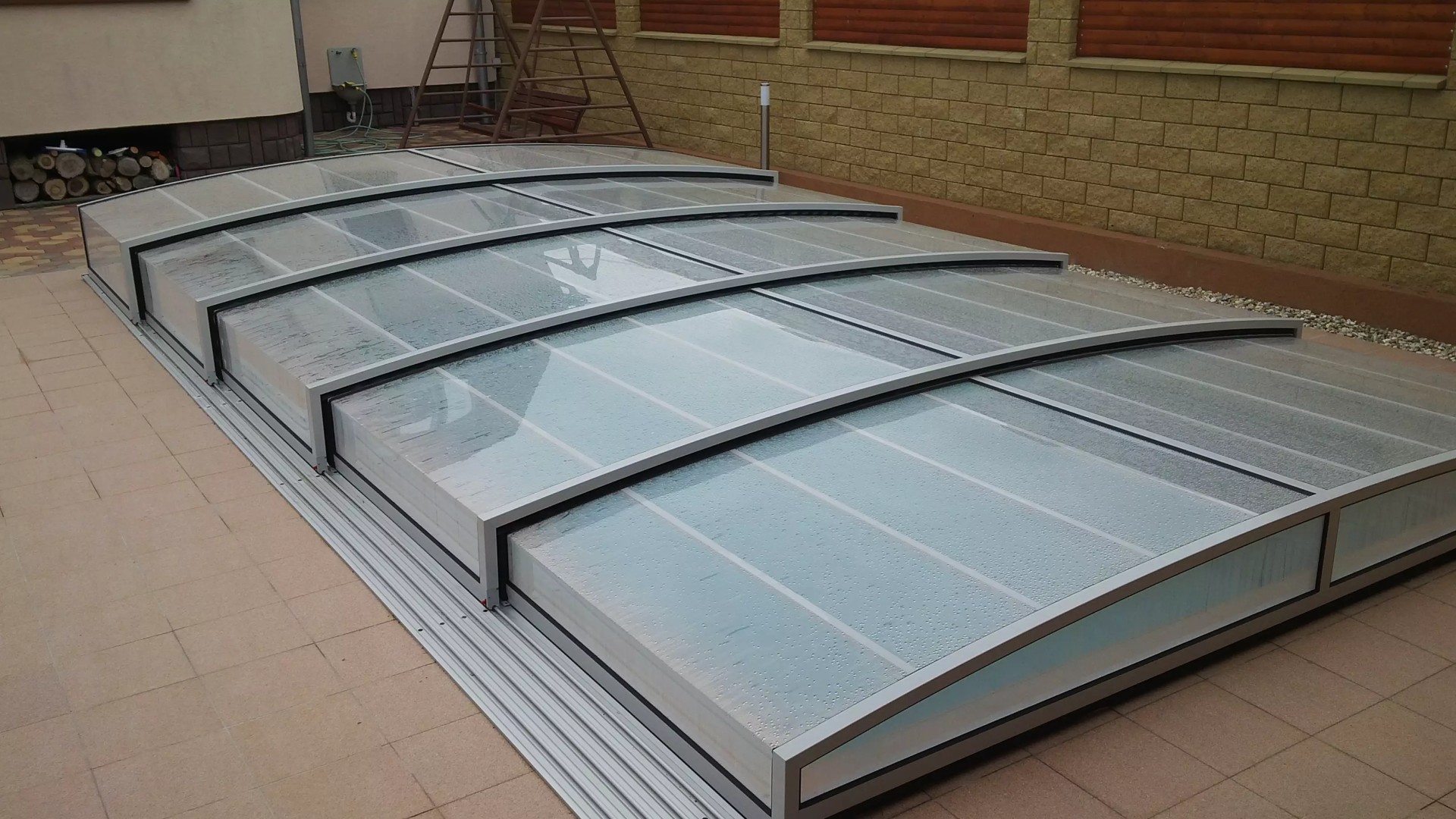 Abri de piscine moderne et bas, doté d'une structure en aluminium et d'un matériau de remplissage transparent.