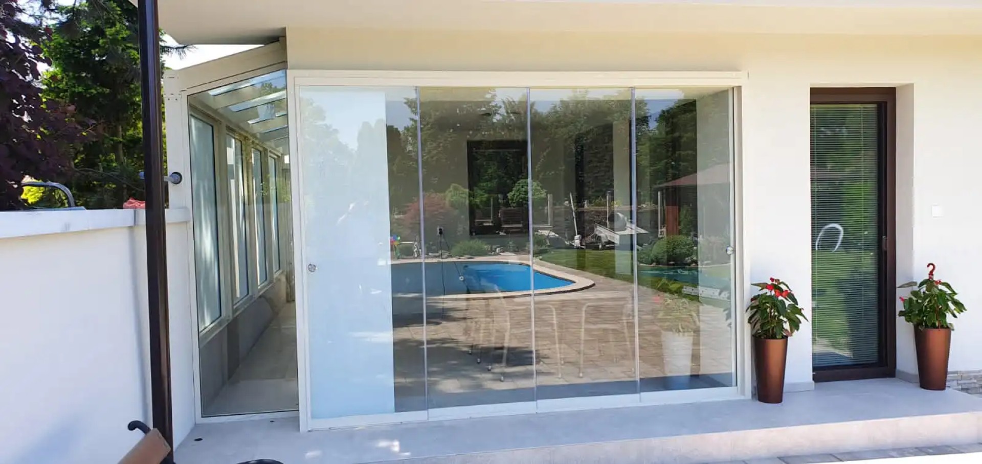 Vitrage moderne sans cadre de la terrasse d'une maison individuelle donnant sur la piscine