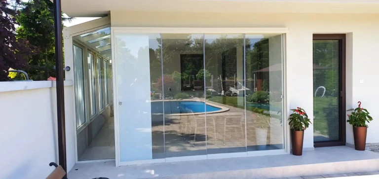 Vitrage moderne sans cadre de la terrasse d'une maison individuelle donnant sur la piscine