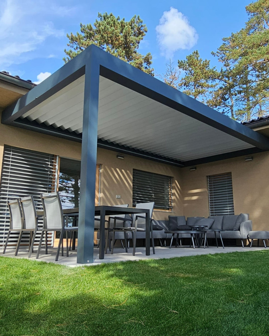 Une pergola bioclimatique moderne avec une structure en aluminium et des lames orientables sur la terrasse d'une maison individuelle