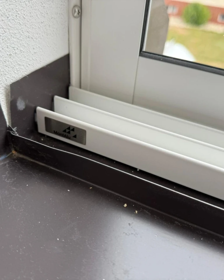 Vue détaillée de la glissière inférieure et du joint du profilé en aluminium du vitrage, avec le logo MontAl.