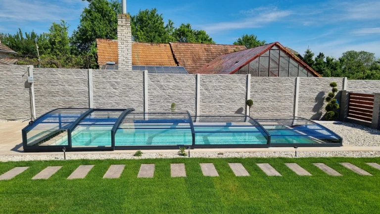 Un abri de piscine moderne et bas, avec une structure anthracite, dans le jardin