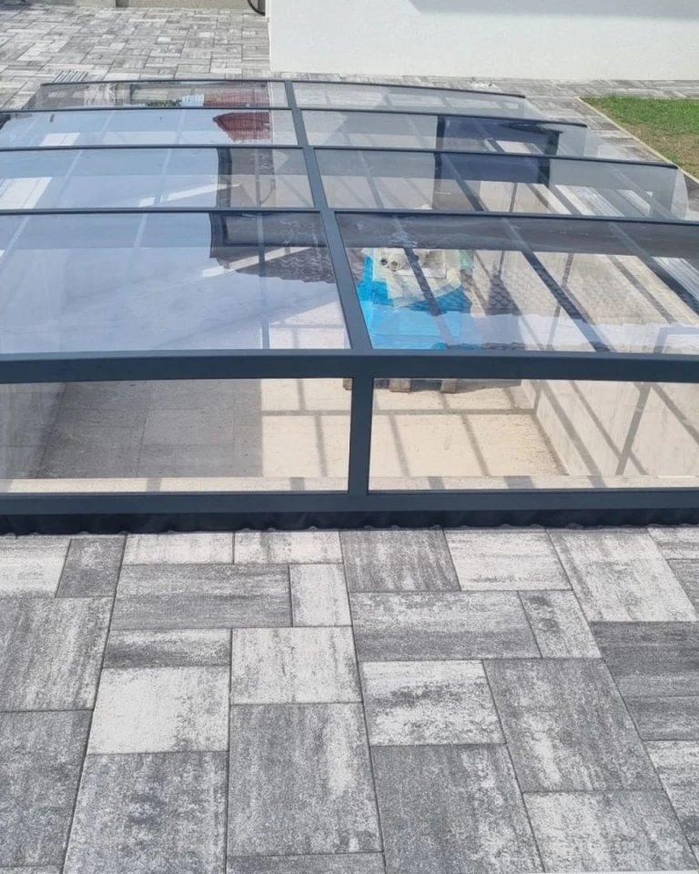 Abri de piscine moderne et bas, avec une structure anthracite et du polycarbonate transparent