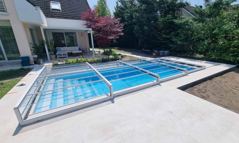 Une couverture de piscine moderne, basse et sans rail, dans le jardin d'une maison individuelle