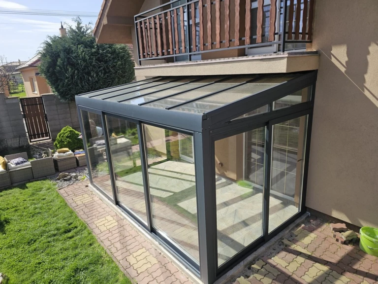 Une véranda moderne vitrée, dotée d'une structure en aluminium anthracite, adossée à une maison individuelle