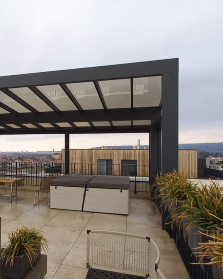 Une pergola moderne en aluminium sur une terrasse sur le toit avec vue sur la ville et un jacuzzi