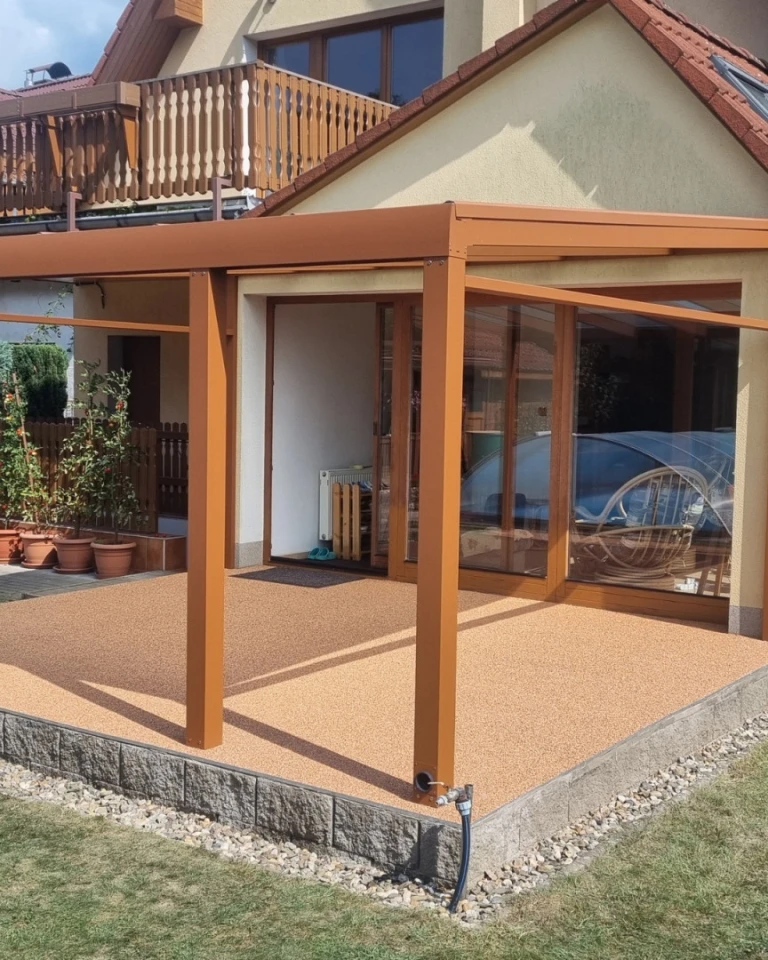 Une pergola moderne en aluminium marron avec des parois en verre sur la terrasse d'une maison individuelle.