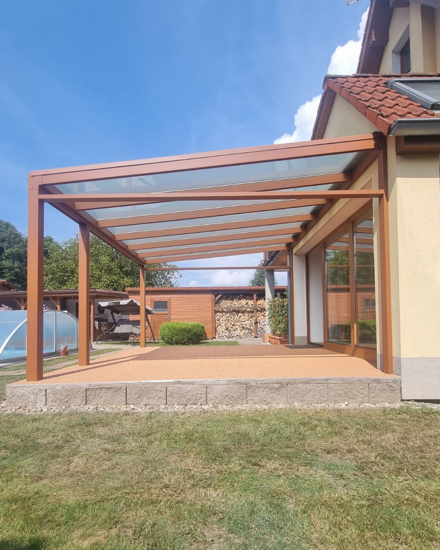 Pergola en aluminium marron avec toit en verre, attenante à une maison individuelle