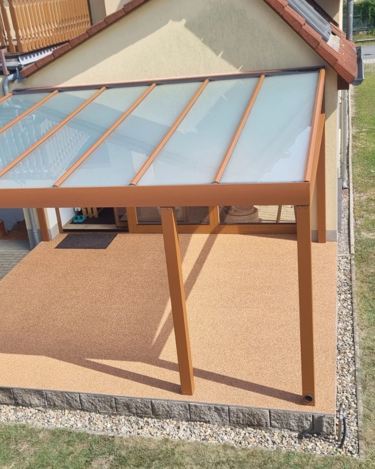 Pergola moderne en aluminium avec vitrage laiteux et structure marron, fixée au mur de la maison