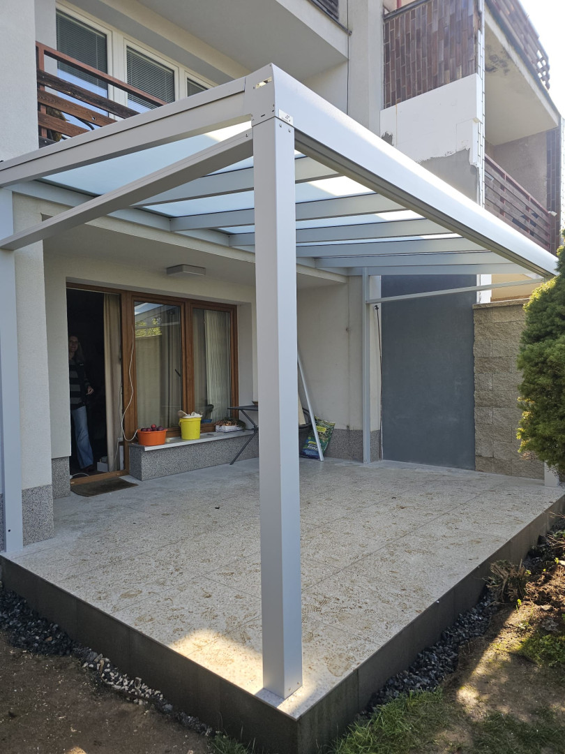 Une pergola moderne en aluminium avec un toit en verre sur la terrasse d'une maison individuelle