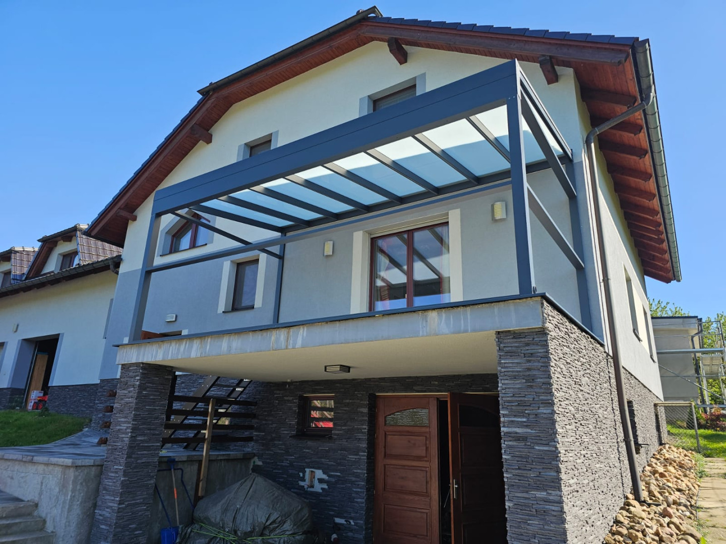 Une pergola moderne en aluminium avec un toit en verre, installée sur le balcon d'une maison individuelle