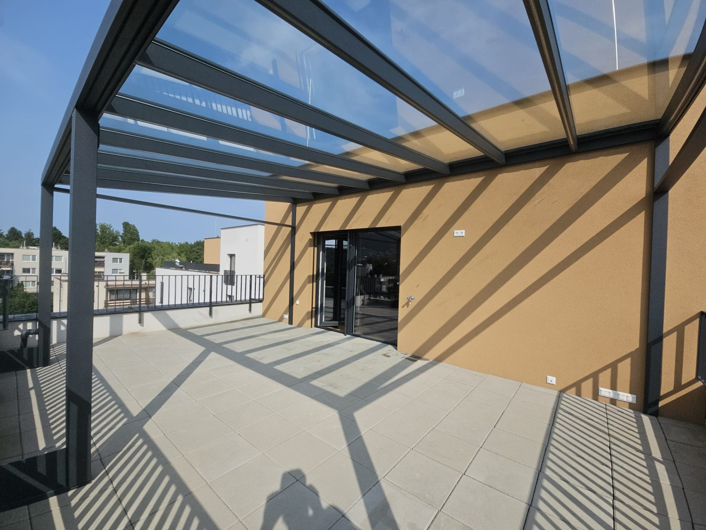 Une pergola moderne en aluminium avec un toit vitré sur la terrasse d'un immeuble d'habitation
