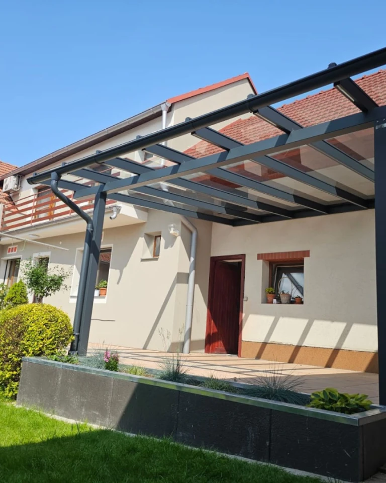 Pergola moderne en aluminium anthracite avec toit en verre, adossée à une maison individuelle