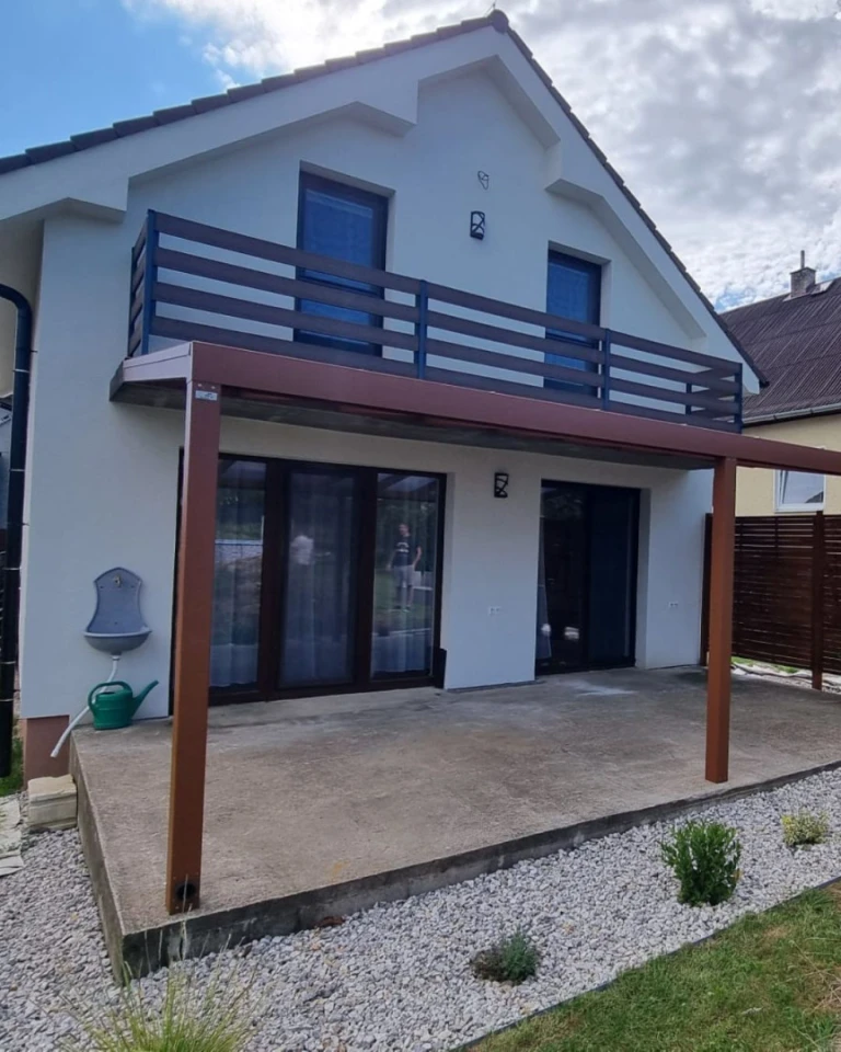 Structure en aluminium marron de la pergola « Robust » sur la terrasse en béton d'une maison individuelle