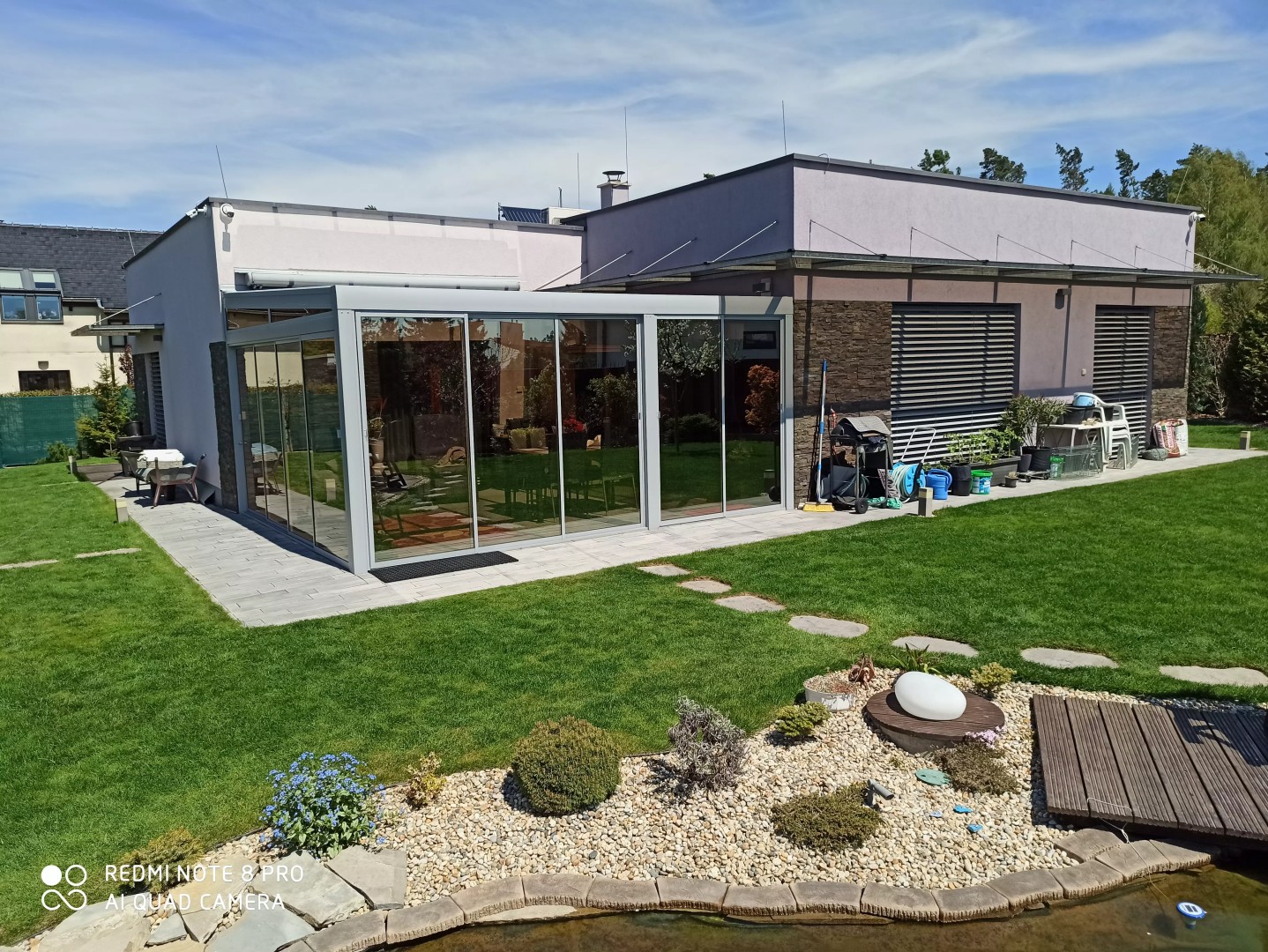 Une pergola moderne en aluminium avec vitrage, installée dans le jardin d'une maison individuelle