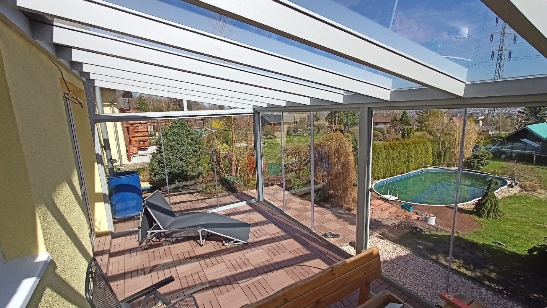 Une pergola moderne en aluminium et verre, avec une terrasse et une vue sur le jardin et la piscine