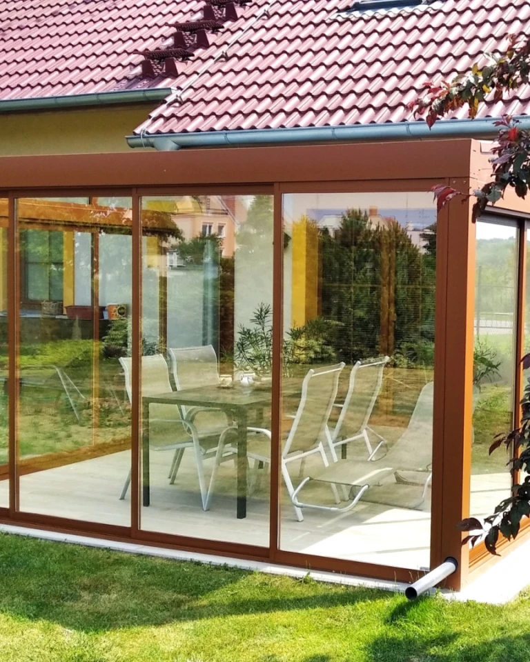 Véranda vitrée en aluminium avec un cadre marron et du mobilier de jardin à Nitra.