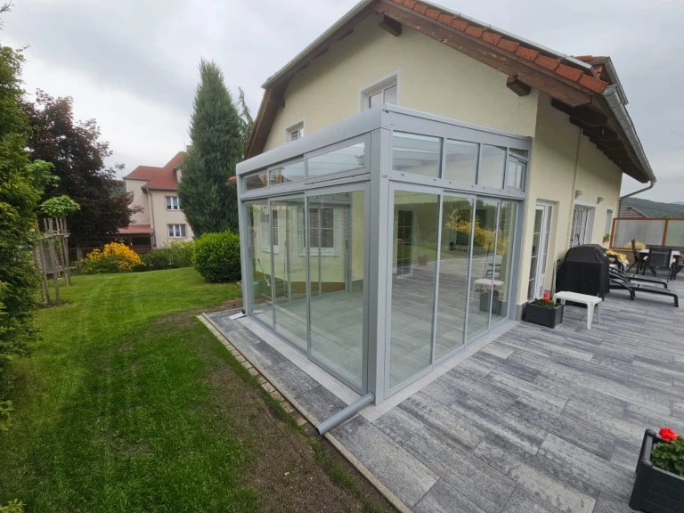 Une véranda moderne vitrée, dotée d'une structure en aluminium, adossée à une maison individuelle
