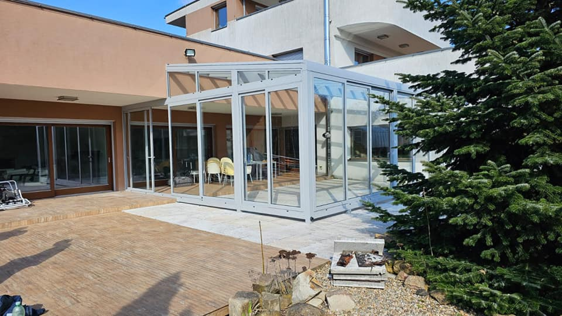 Une véranda moderne en aluminium avec des portes coulissantes en verre, adossée à une maison individuelle