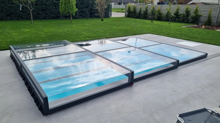 Une couverture de piscine moderne et basse en aluminium, dotée d'un revêtement transparent, dans le jardin