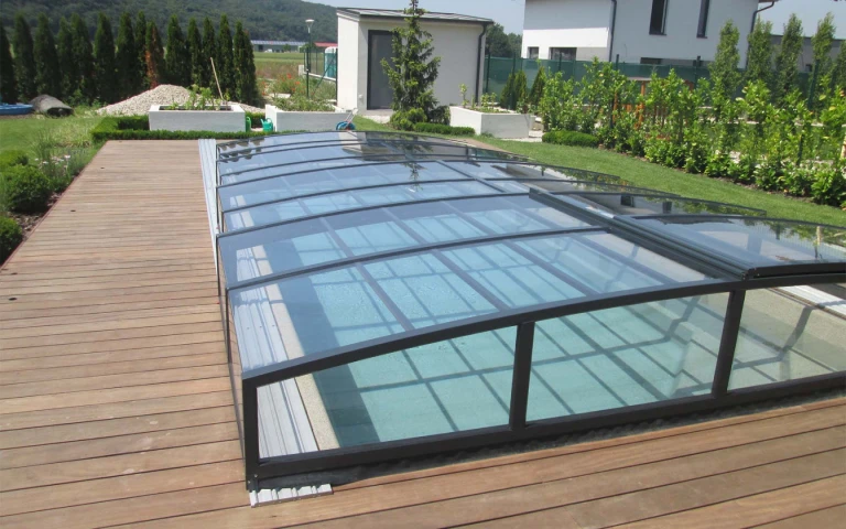 Une couverture de piscine moderne et basse en aluminium, de couleur foncée, installée sur une terrasse en bois