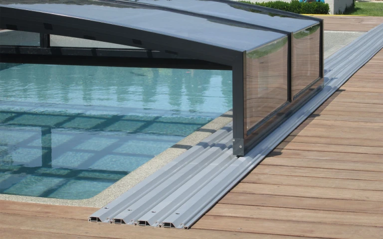 Vue détaillée du rail et de la structure de la petite verrière au-dessus de la piscine, sur la terrasse en bois
