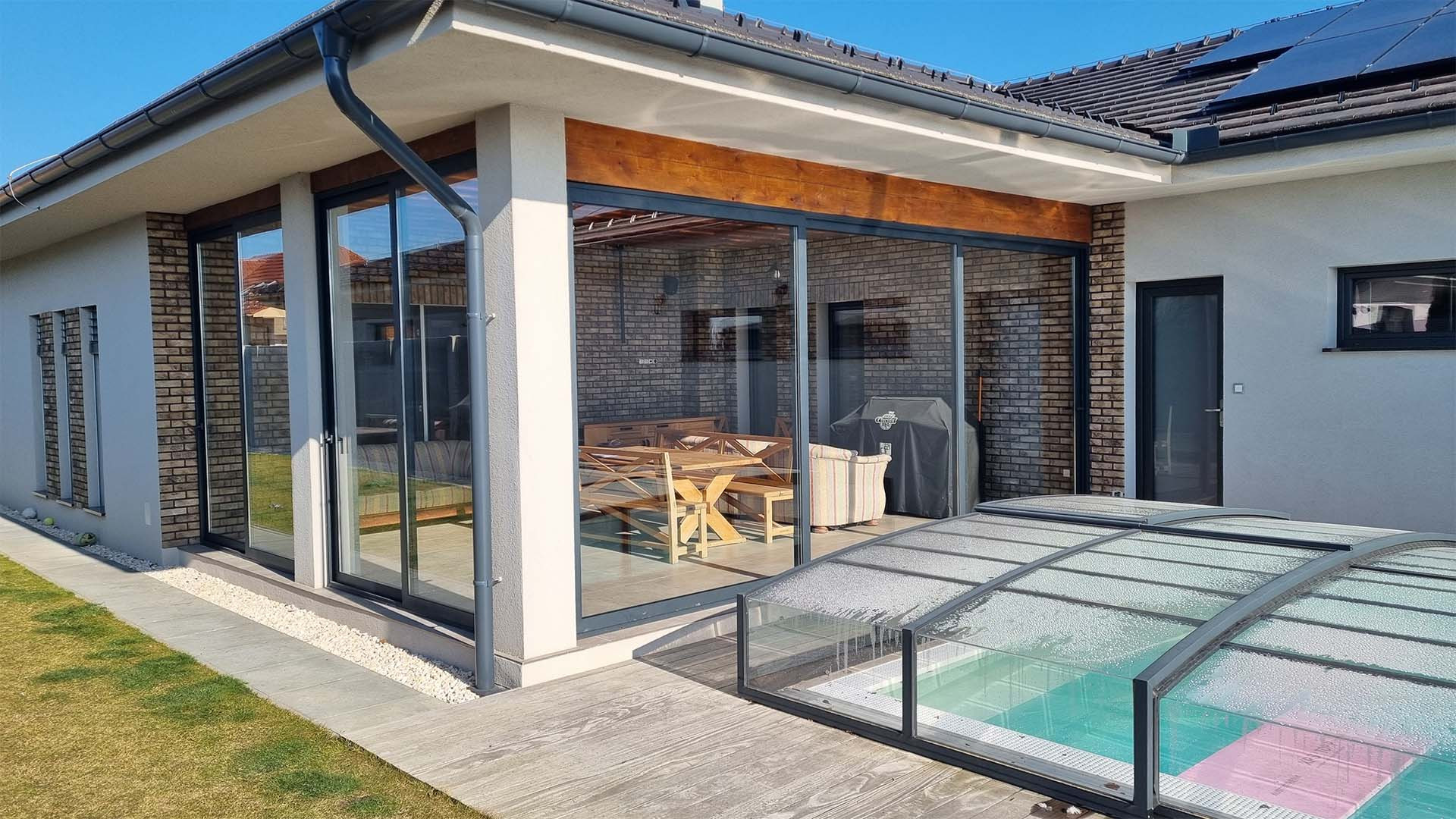 Portes coulissantes modernes en aluminium et verre donnant sur la terrasse d'une maison individuelle avec vue sur la piscine.