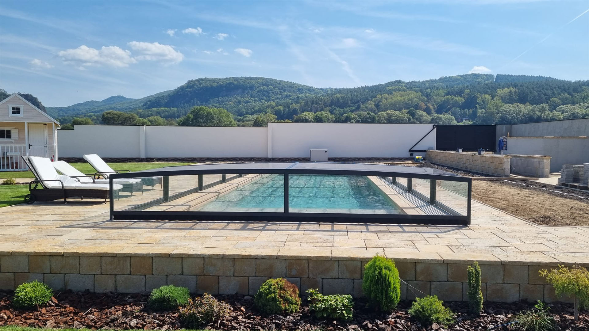 Une couverture de piscine moderne et basse en aluminium dans un jardin avec vue sur les collines