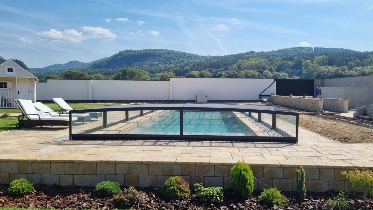 Une couverture de piscine moderne et basse en aluminium dans un jardin avec vue sur les collines