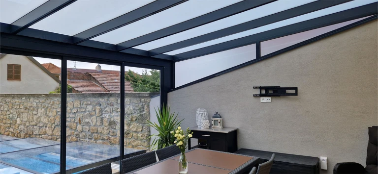 Intérieur moderne de la véranda ROBUST, ne nécessitant aucun entretien, dotée de portes coulissantes en verre et offrant une vue sur la piscine.