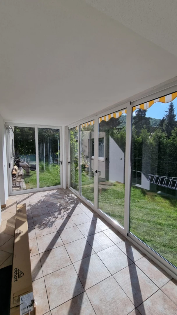 Une terrasse vitrée aux cadres blancs, avec vue sur le jardin