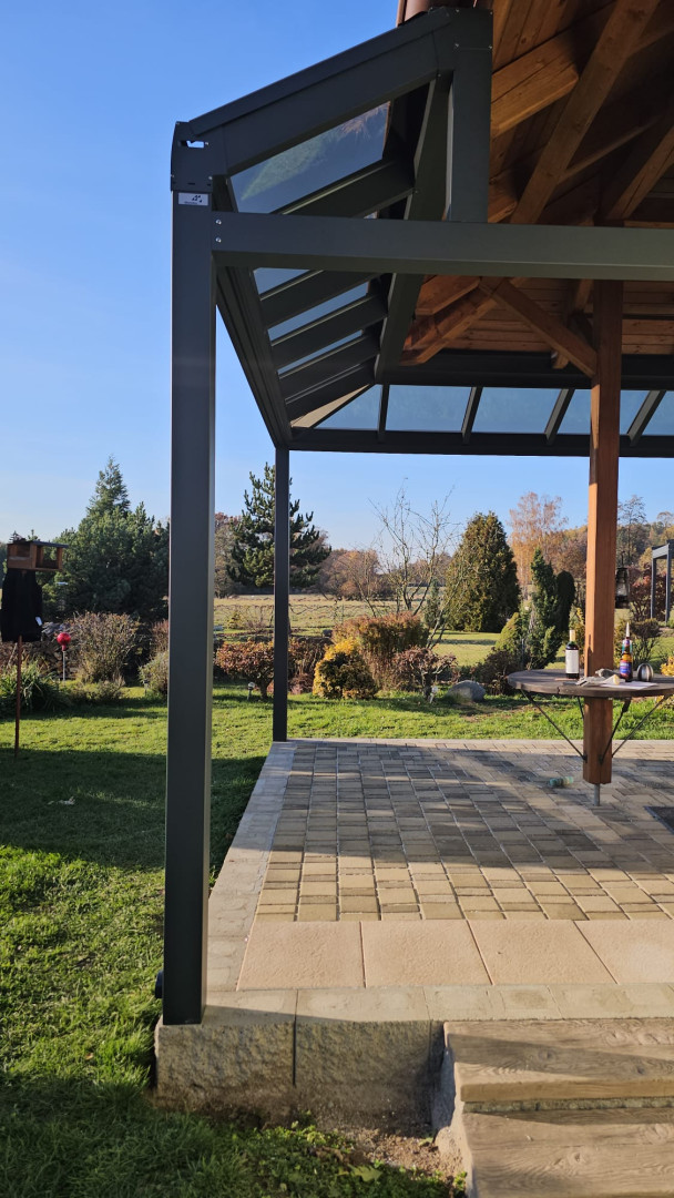Vue détaillée de la structure en aluminium et du toit vitré de la pergola, avec vue sur le jardin.