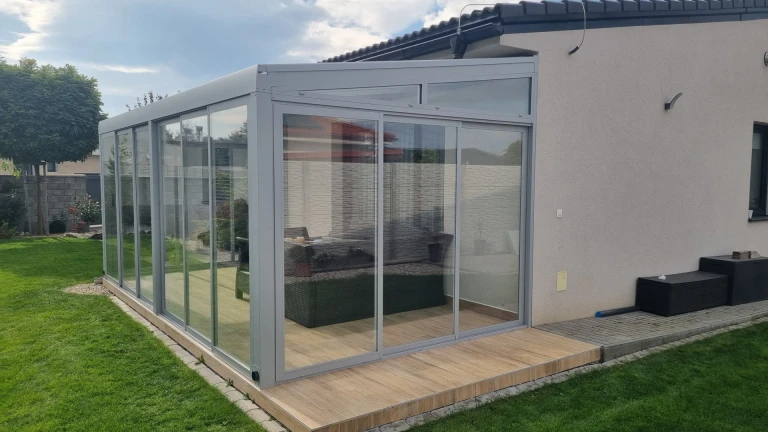 Une véranda moderne vitrée, dotée d'une structure en aluminium, adossée à une maison individuelle