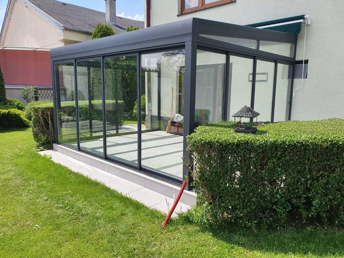 Une véranda moderne vitrée, dotée d'une structure en aluminium anthracite, construite dans le jardin d'une maison individuelle