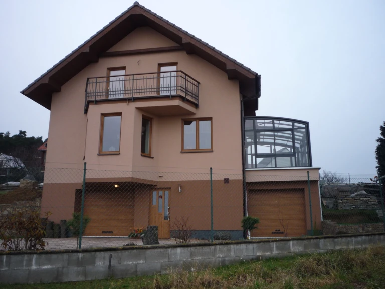 Vue d'une maison familiale dotée d'une extension sous forme de véranda vitrée coulissante, située sur la terrasse au-dessus du garage.