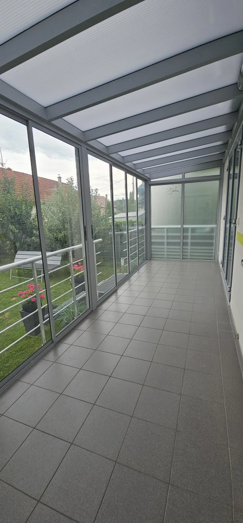 Intérieur d'une véranda vitrée donnant sur un jardin verdoyant